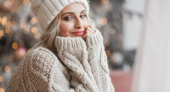 Close up portrait of young beautiful woman on Christmas background. Smiling girl with perfect skin near the Christmas tree.