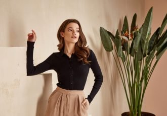 Beautiful brunette woman natural make up wear fashion clothes casual dress code office style black blouse and beige pants suit for romantic date business meeting accessory interior stairs flowerpot.